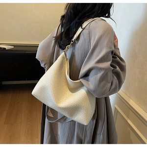 Texture tressée détaillée du sac hobo crème avec des ferrures dorées et cuir souple