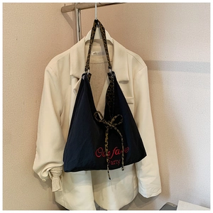 Détail du sac fourre-tout en toile avec anse léopard, nœud papillon et broderie rouge