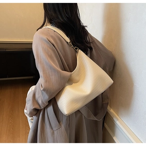Détail d'un sac à bandoulière matelassé beige avec texture fine en similicuir et boucles