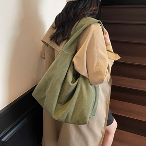Détail d'un grand sac hobo en velours côtelé vert mousse sur un escalier en bois