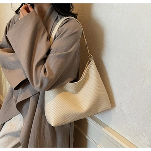 Détail d'un sac à bandoulière tressé crème avec boucle dorée et texture élégante