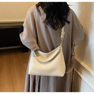 Détails de texture tressée et boucle dorée sur un sac hobo beige porté par un mannequin