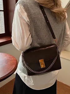 Sac bandoulière rétro marron foncé avec boucle dorée et chaîne sur modèle femme