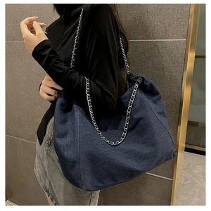 Detail view of large denim tote bag with silver chain strap and slouchy design
