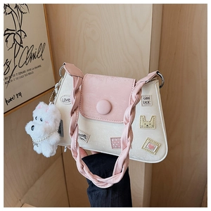 Detalle de bolso bandolera beige y rosa con parches bordados y correa trenzada
