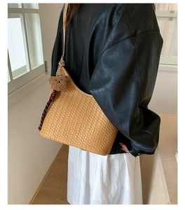 Detail of light brown woven hobo bag with a cute bear charm pendant for women
