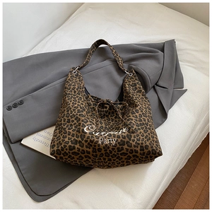 Détail du cabas léopard avec fermeture à nouer et lettrage blanc sur un blazer gris