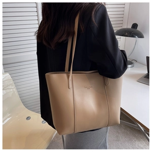 Gros plan d'un sac cabas en simili cuir kaki avec logo gaufré porté par un mannequin