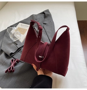 Detail view of burgundy suede underarm bag with adjustable buckle strap and extra long strap