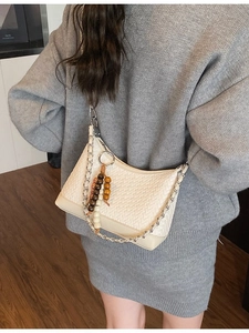 Retro cream woven crossbody bag with silver chain and bead pendant shown on a model