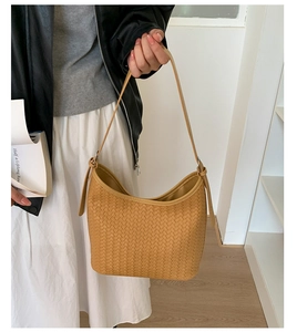 Close-up detail of the intricate brown woven texture on a minimalist crescent bucket bag