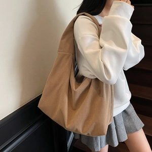 Détail de la texture d'un sac cabas en velours côtelé marron porté par un mannequin