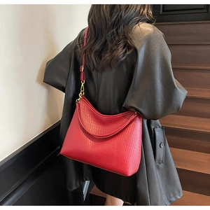 Détail du cabas en cuir tressé rouge avec boucles dorées et bandoulière réglable