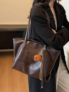 Deep coffee large PU leather tote bag with teddy charm shown on shoulder for daily commute