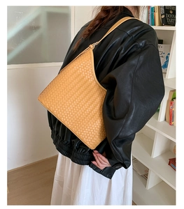 Detail of hand-woven ginger leather bucket bag featuring a classic Intrecciato pattern