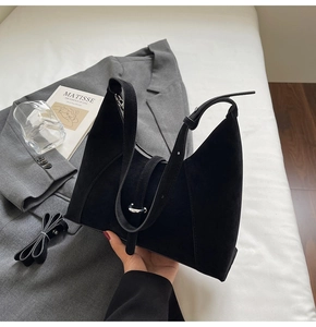 Detail of minimalist black suede crescent bag with silver zipper and long strap