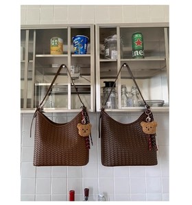 Close-up of woven bucket bags with leather straps and cute plush bear keychains