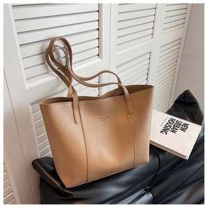 Détail d'un grand cabas en cuir beige avec logo Fashion Trend sur un canapé noir