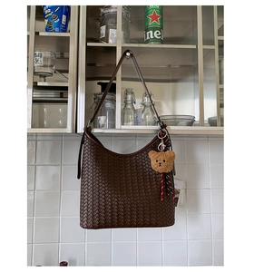 Detail of dark brown woven hobo bag with thick texture and cute bear pendant charm