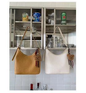 Macro detail of high-quality woven hobo bags in yellow and white with teddy charm