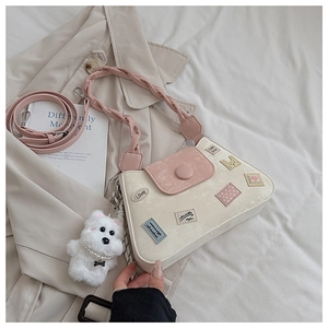 Detalle de un bolso cubo crema y rosa con parches lindos sobre una gabardina beige