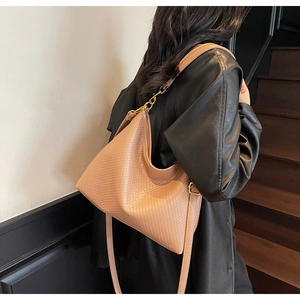 Détail d'un grand sac hobo tissé beige montrant la texture et la boucle en métal doré