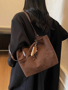 Brown faux suede tote bag with beaded charm and shoulder strap for office commuting