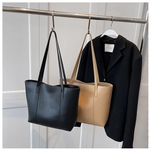 Vue détaillée de grands sacs cabas en cuir noir et beige suspendus sur des cintres