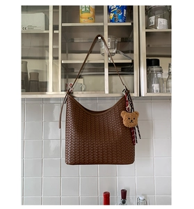 Detailed texture of brown woven hobo bag with teddy charm and silk scarf on strap