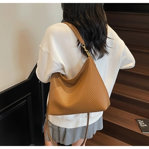 Détail de texture du sac hobo marron en cuir tressé avec boucle en métal doré chic