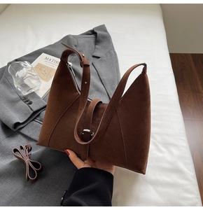 Detail of dark brown suede shoulder bag showing metal zipper and adjustable handle strap