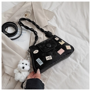 Detalle de bolso hobo de ante negro con parches de dibujos y colgante de perro de peluche
