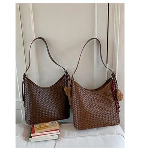 Detail of woven texture on caramel shoulder bag with adjustable strap and charm
