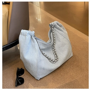 Detail of light blue denim tote bag with drawstring closure and silver chain strap