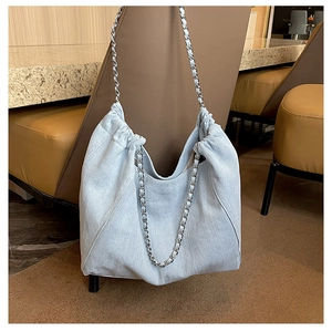 Detail of light blue denim hobo bag featuring pleated opening and metal chain strap