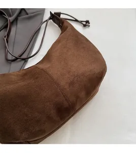 Detailed view of dark brown suede crescent bag with textured stitching and drawstrings