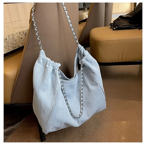 Detail of light blue denim tote bag with drawstring closure and silver chain strap