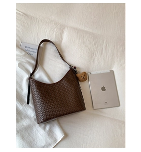 Flat lay of brown woven bucket bag with bear pendant and iPad for size comparison