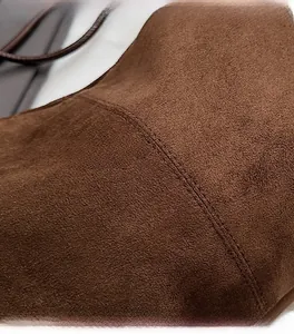 Close-up of precise double-row stitching on high-quality brown suede shoulder bag