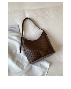 Close-up of the woven leather texture and curved saddle silhouette of this brown bucket bag