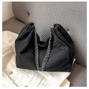 Detail of black denim tote bag with silver chain strap and drawstring pleat texture
