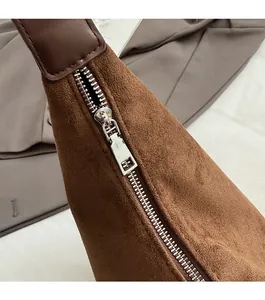 Detail of silver zipper and reinforced stitching on brown suede shoulder bag