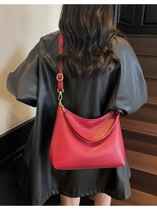 Grand sac bandoulière rouge en similicuir tressé présenté de dos par un mannequin