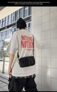 Detail of multi-pocket black utility crossbody bag with buckles on a streetwear model
