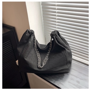Detail of dark denim tote bag featuring pleated drawstring closure and metal chain strap