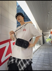 Outdoor street style shot of black nylon utility crossbody bag with multiple pockets