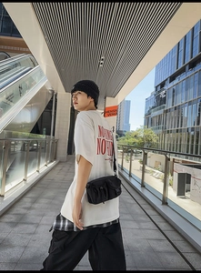 Detail of a black nylon crossbody bag with drawstring pockets in urban streetwear style