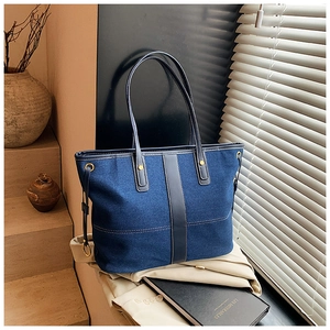Detail of dark blue denim tote bag with leather straps and gold drawstring hardware