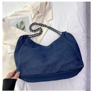 Detail of blue denim tote bag featuring silver chain strap and durable fabric texture