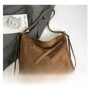 Close-up of brown suede tote bag with decorative buckle on gray suit fabric